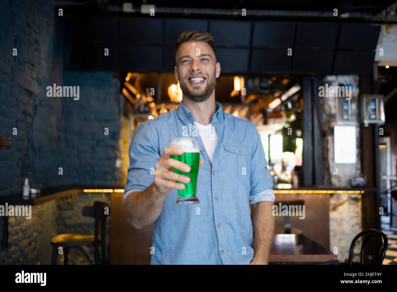 Bell'uomo che tiene una birra in un pub per il giorno di San Patrizio Foto Stock