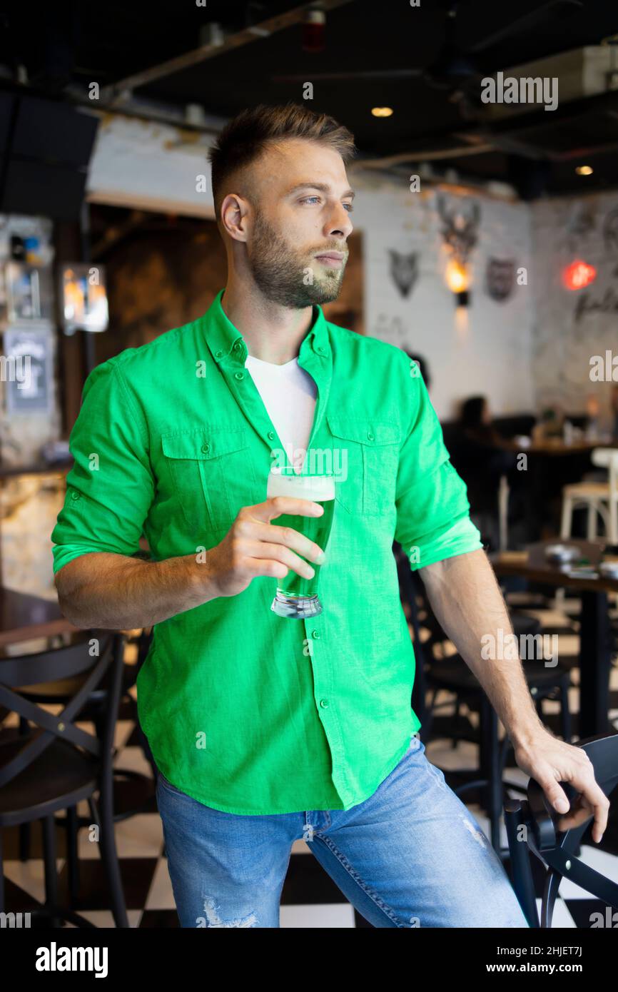 Bell'uomo verde che tiene la sua birra in un pub per il giorno di San Patrizio Foto Stock