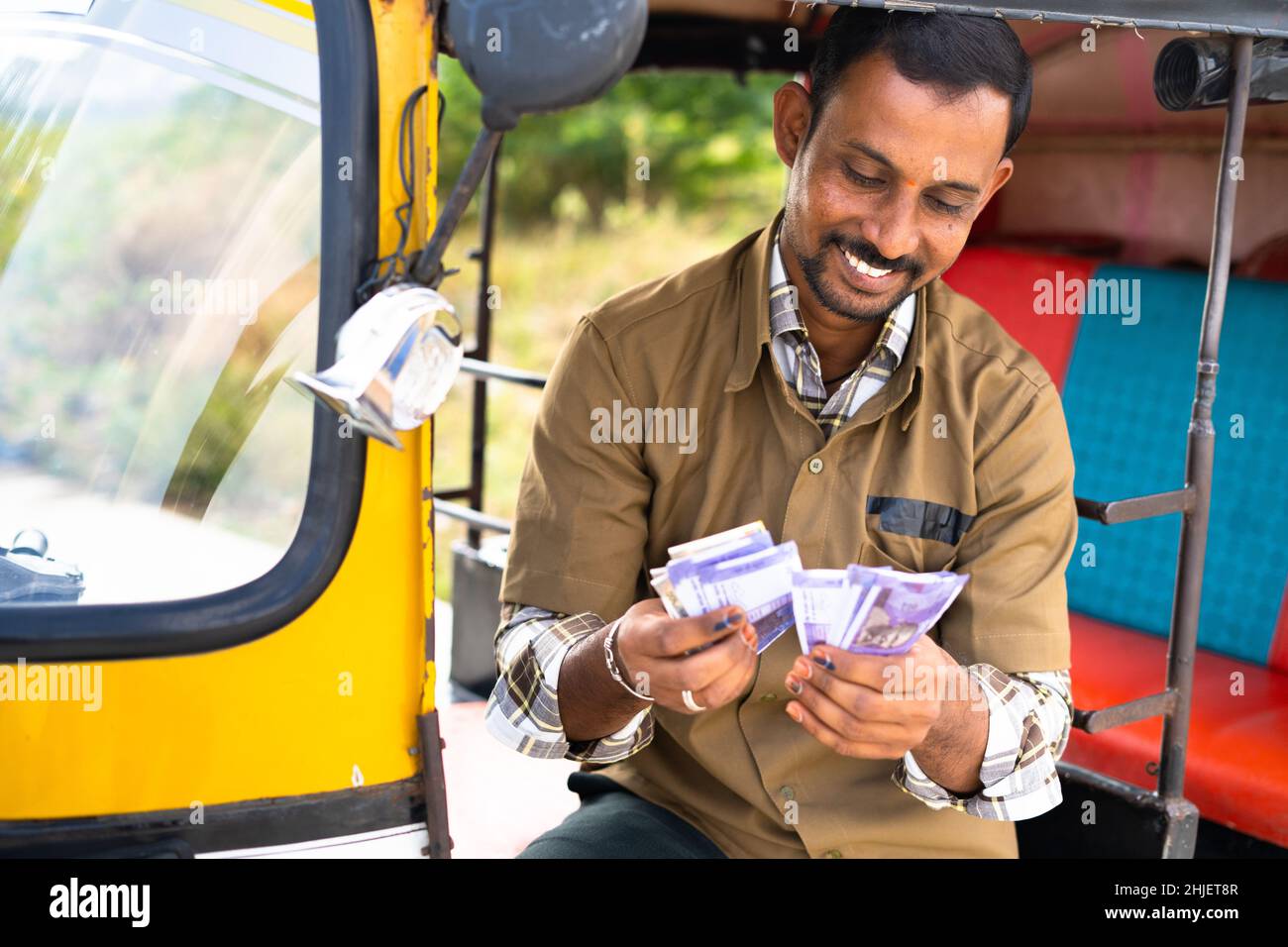 Felice sorridente auto Rickshaw conducente contando soldi da dentro auto - concetto di successo di business, approvazione di prestito, finanziario, bancario e di sé Foto Stock