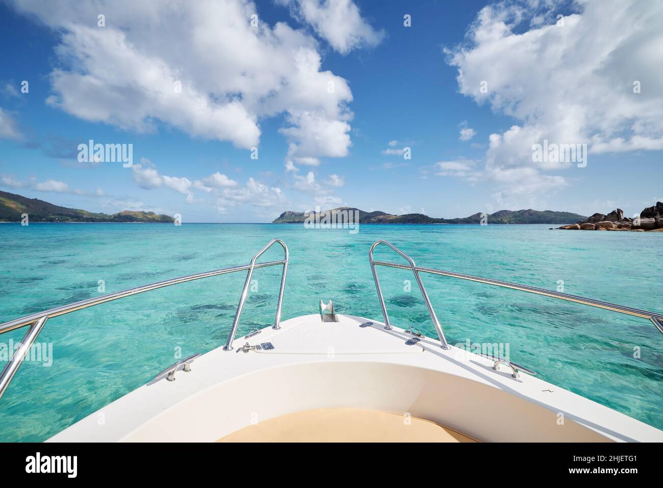 Prua di nave in mare con acqua turchese tra isole tropicali in giorno di sole. Isola di Praslin, Seychelles Foto Stock