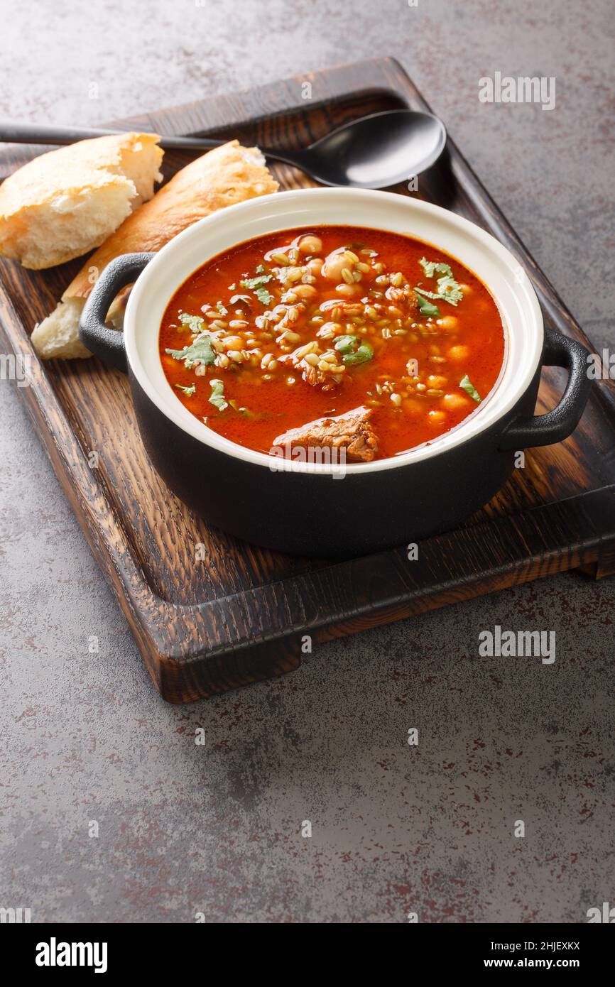 Chorba Hamra bel Frik Algerino Agnello, Tomato, e Freekeh Soup primo piano in un piatto sul tavolo. Verticale Foto Stock