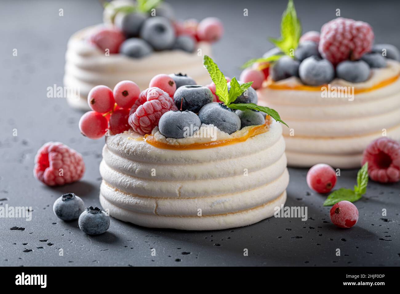 Mini dessert Pavlova fatto in casa con meringa e frutti di bosco surgelati. Dessert a base di meringa con frutti di bosco surgelati e panna. Foto Stock