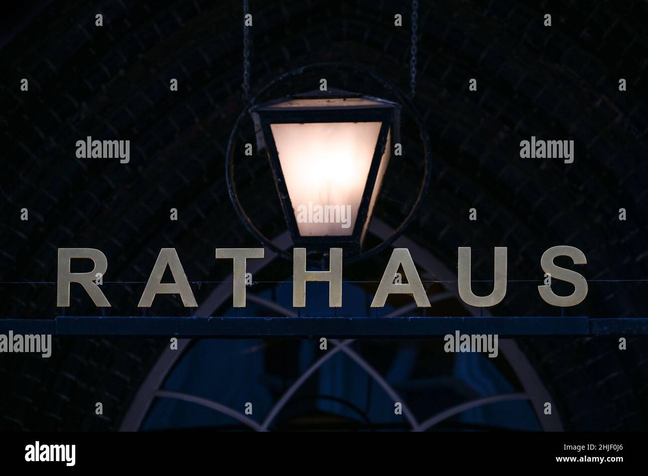 Edificio iscrizione Rathaus (parola tedesca per il municipio) sotto una lanterna di fronte ad una facciata storica scura di notte a Lubeck, Germania, spazio copia, s Foto Stock