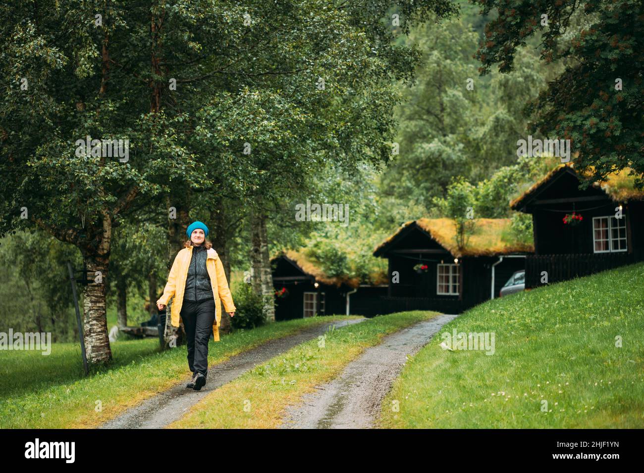 Giovane donna Tourist Lady Walking vicino tradizionale norvegese Case di legno antico con Grass crescente sul tetto. Cabine in Norvegia Foto Stock