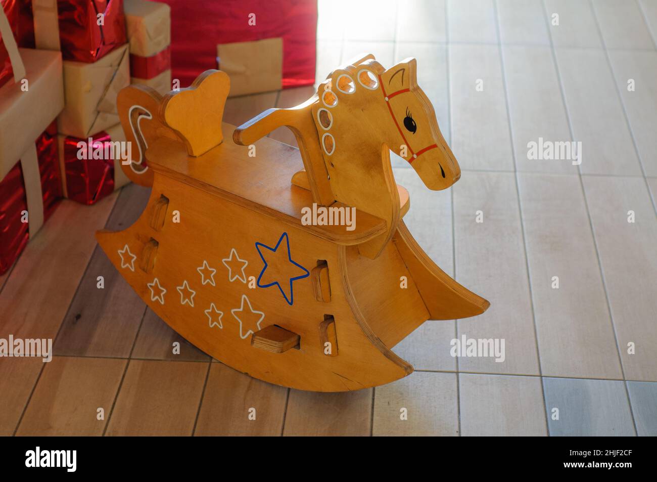 Cavallo dondolo in legno per bambini, scena natalizia, regali sotto l'albero di Capodanno, soft backlight. Foto Stock