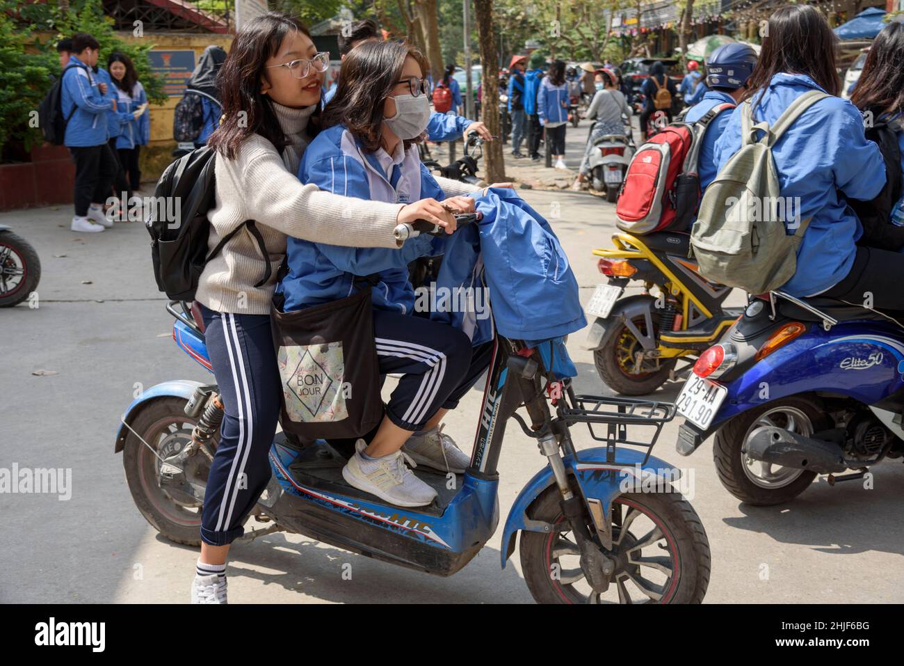 Gli scolari vietnamiti, indossando le loro uniformi blu, lasciano la scuola a pranzo ad Hanoi, Vietnam, Asia sudorientale Foto Stock