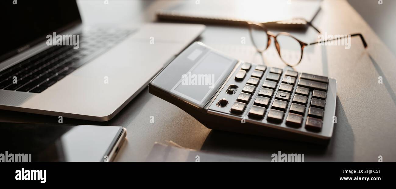 Luogo di lavoro a casa, calcolatrice, computer portatile sulla scrivania. Pianificazione finanziaria, consulente, contabile, bancario Foto Stock