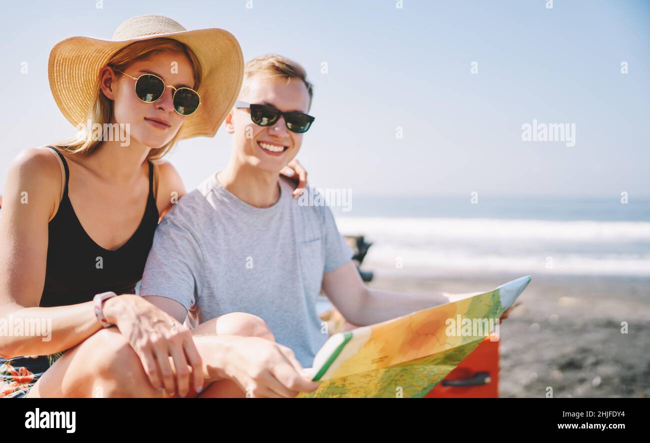 Coppia allegra seduta sulla spiaggia con mappa Foto Stock