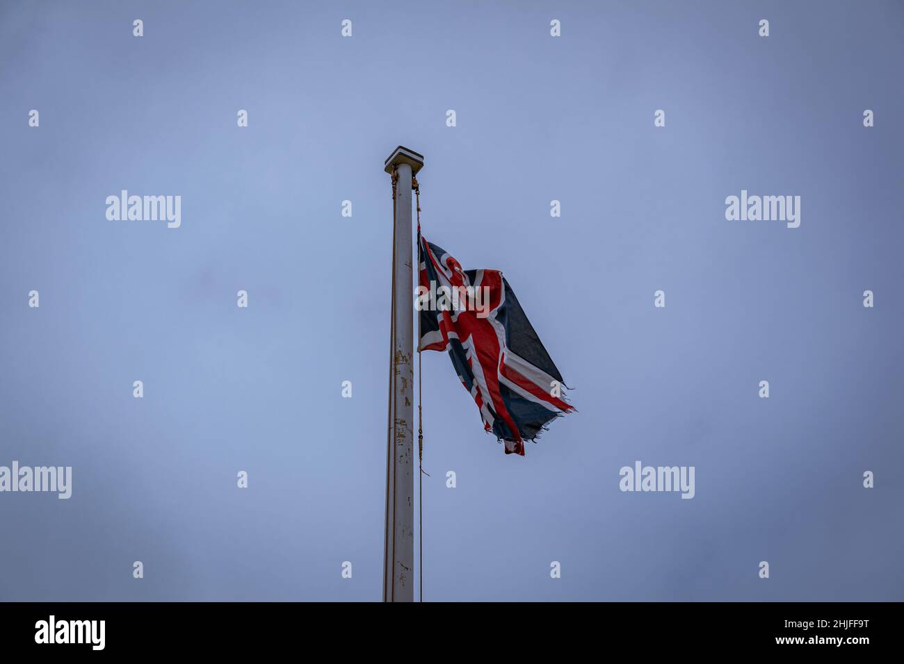 bandiera britannica tattered che vola in alto nel cielo blu Foto Stock