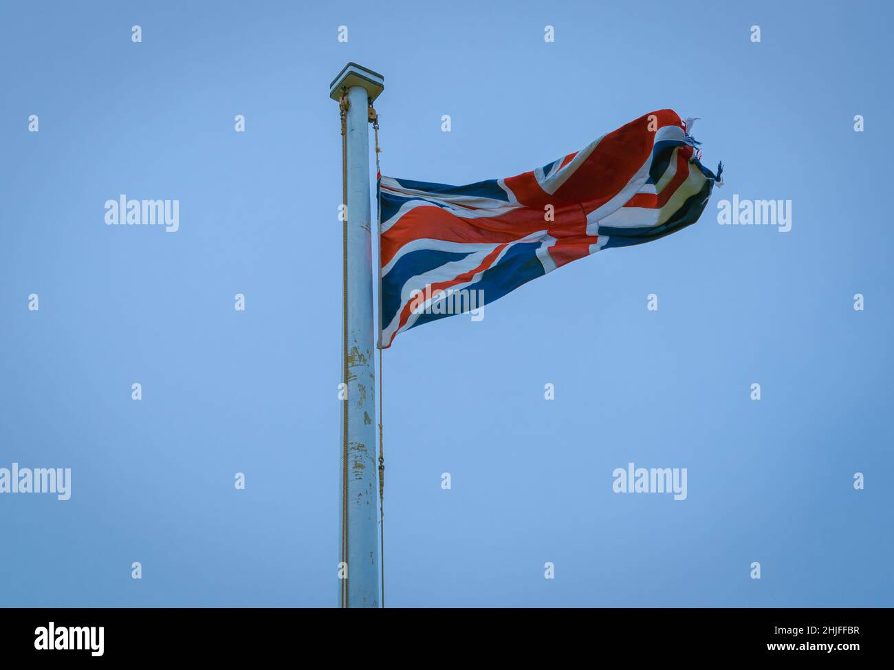 bandiera britannica tattered che vola in alto nel cielo blu Foto Stock