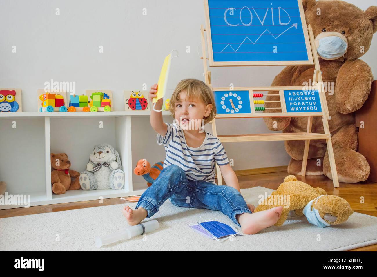 Carino bambino ragazzo in quarantena casa giocando medico sul pavimento con i suoi orsacchiotti malati indossare maschere mediche durante coronavirus COVID-2019 focolaio Foto Stock