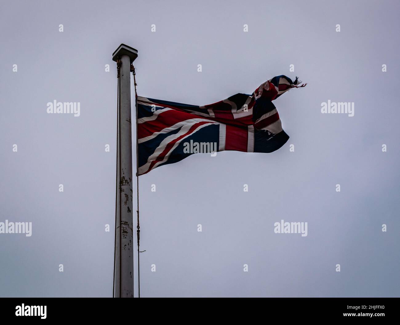 bandiera britannica tattered che vola in alto nel cielo blu Foto Stock