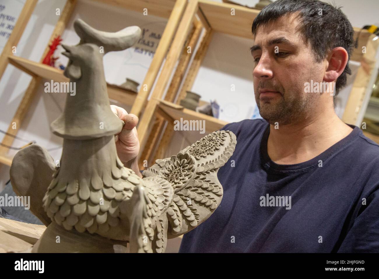 Mosca, Russia. 18th dicembre 2021 Un maestro scolpisce un giocattolo in argilla durante un laboratorio nel tradizionale stile russo del giocattolo Abashevskaya alla fiera-mostra di artigianato popolare di Russia 'Ladya' presso l'ExpoCenter di Mosca, Russia Foto Stock