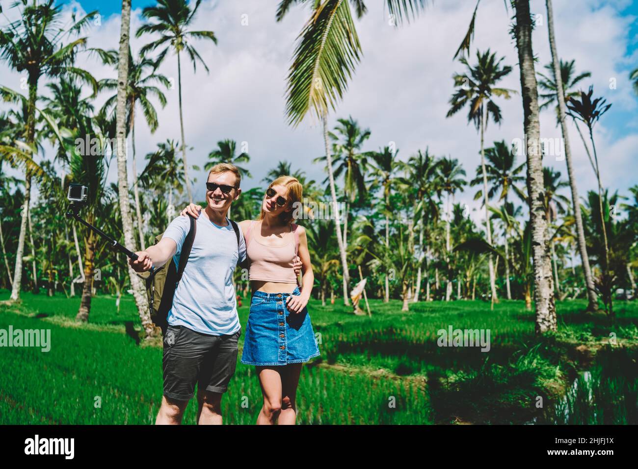 Coppia viaggiante con bastone selfie in campi tropicali Foto Stock