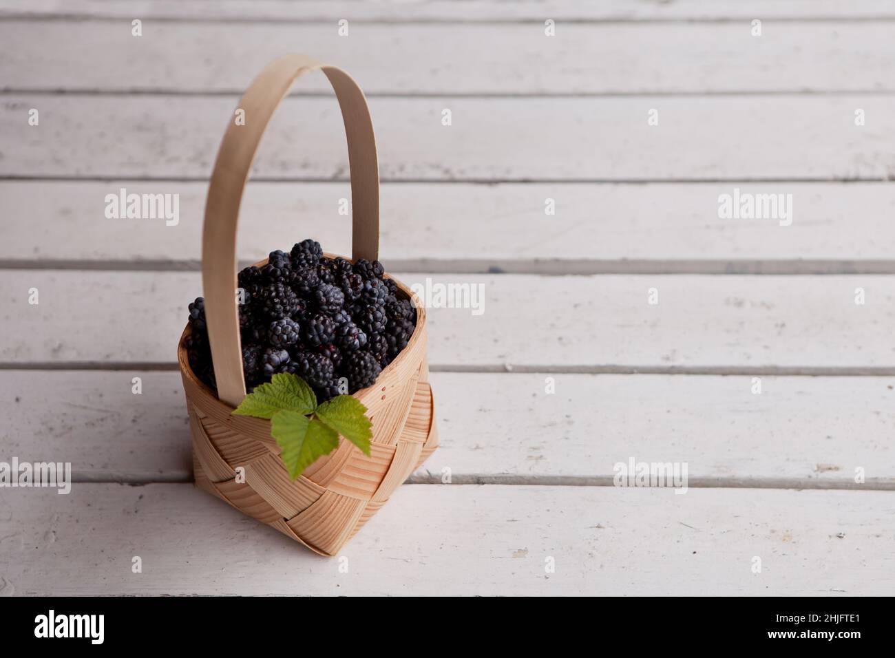 Bacche fresche in un cestino. Estate bacche biologiche fattoria su uno sfondo bianco legno Foto Stock