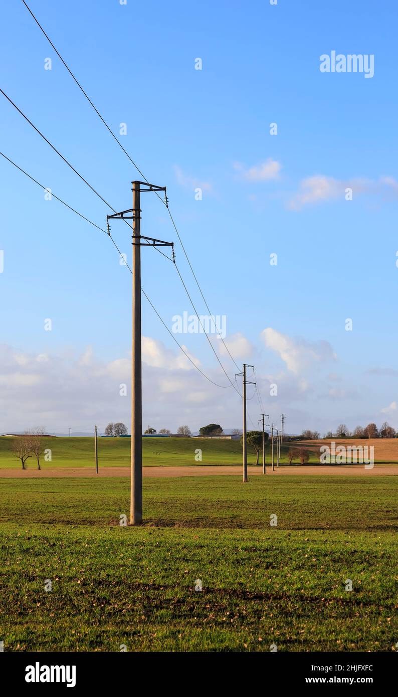 Linee elettriche ad alta tensione nella campagna italiana in una giornata di sole con cielo blu. Foto Stock