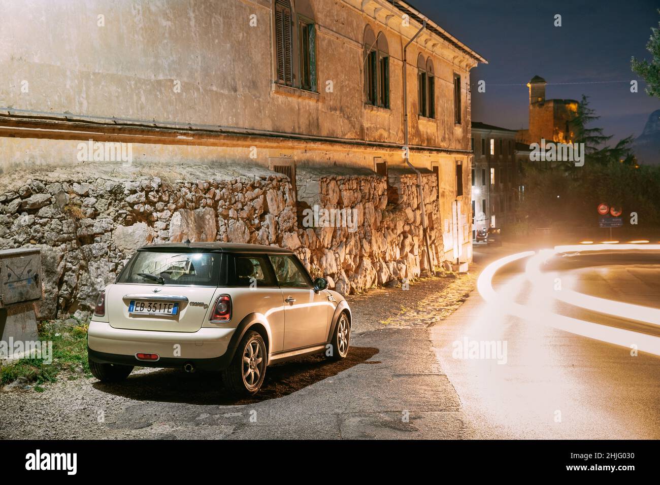 Terracina, Italia. Bianco Colour Hatch Pre-Facelift Mini Cooper R56 Auto parcheggiata sullo sfondo Castello Frangipane in serata luci notturne Foto Stock