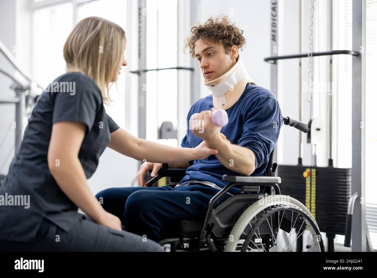 Specialista di riabilitazione con un ragazzo su una sedia a rotelle che fa esercizio Foto Stock