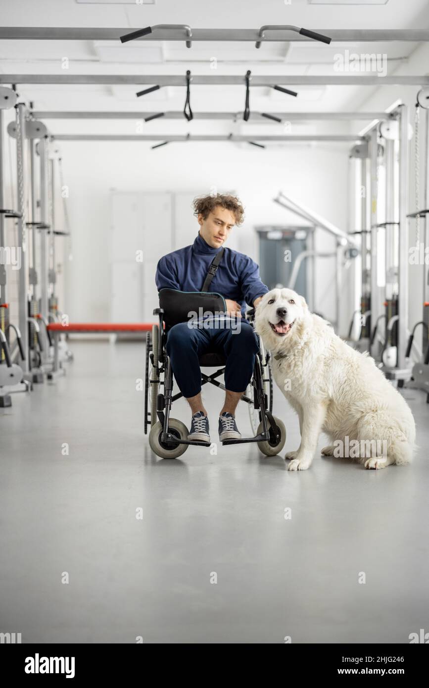 Ragazzo con disabilità in sedia a rotelle con il suo cane di assistenza al centro di riabilitazione Foto Stock