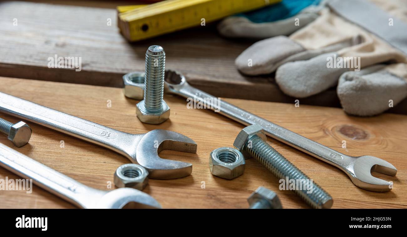Chiave dado e vite su fondo in legno. Attrezzo manuale per riparazione e costruzione su tavolo da officina, vista da primo piano Foto Stock