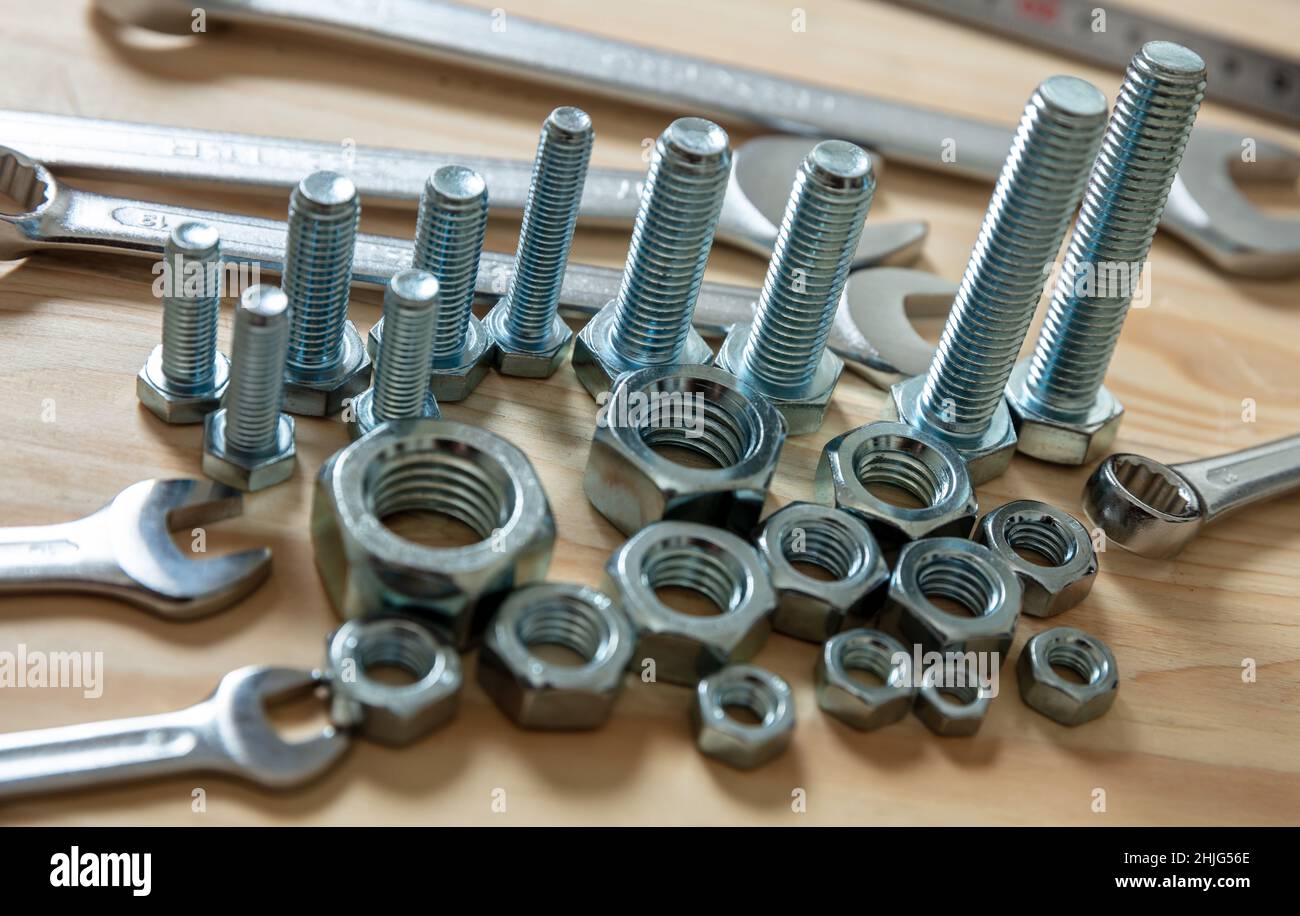 Chiave dado e vite su fondo in legno. Attrezzo manuale per riparazione e costruzione su tavolo da officina, vista da primo piano Foto Stock