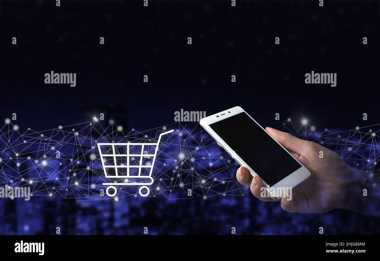 Shopping online, applicazione di negozio online in uno smartphone. Smartphone bianco portatile con cartello con ologramma digitale su sfondo sfocato scuro della città. Foto Stock