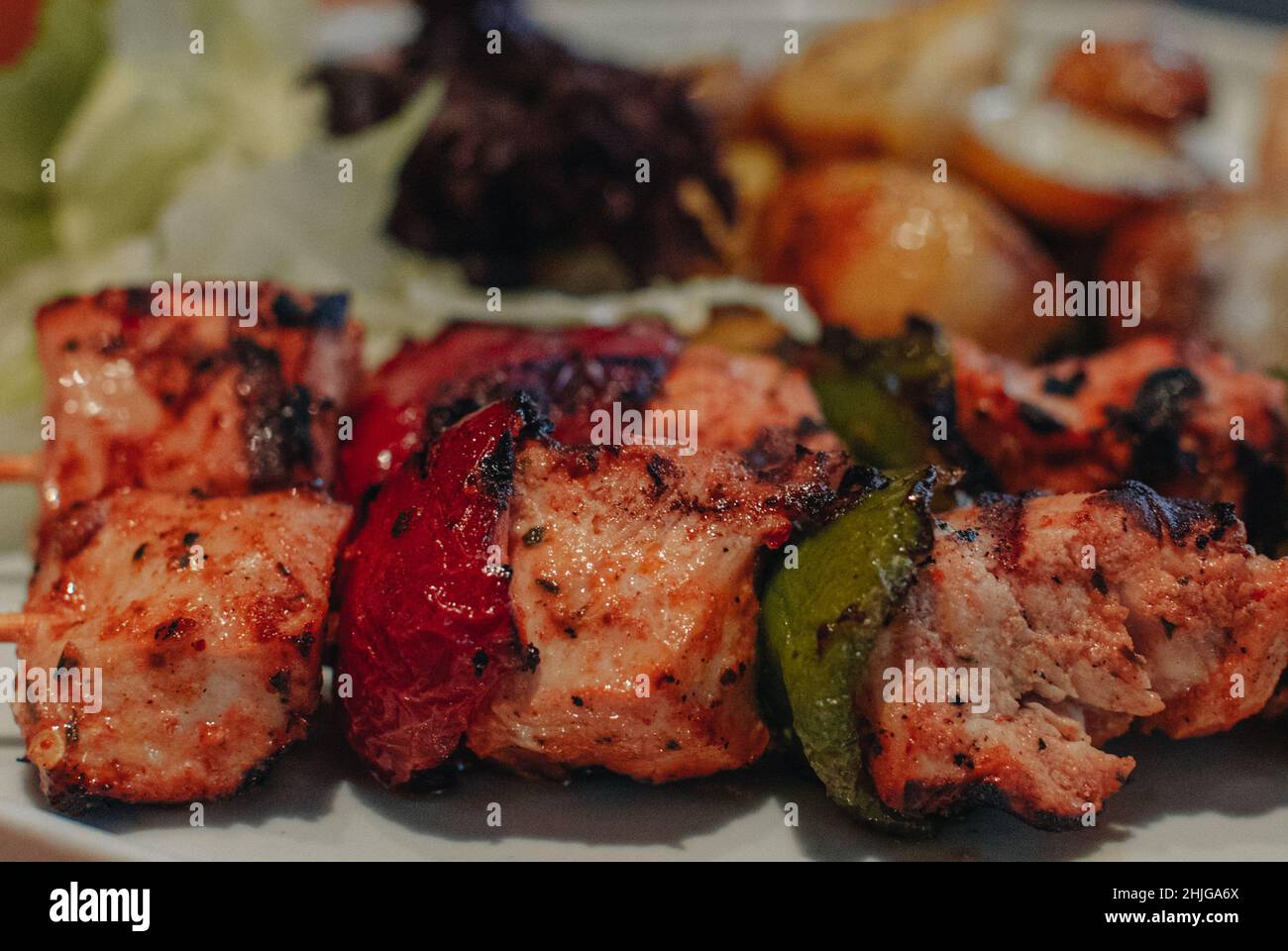 Dettagli ravvicinati degli spiedini di carne bianca con verdure cotte su un piatto. Cena gustosa Foto Stock