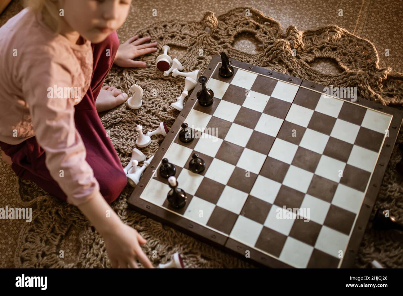 Scacchiera con la fine del gioco degli scacchi. Imparare a giocare a scacchi  per bambini. Pezzi di scacchi sulla tavola illuminata dal sole della casa  sul pavimento Foto stock - Alamy