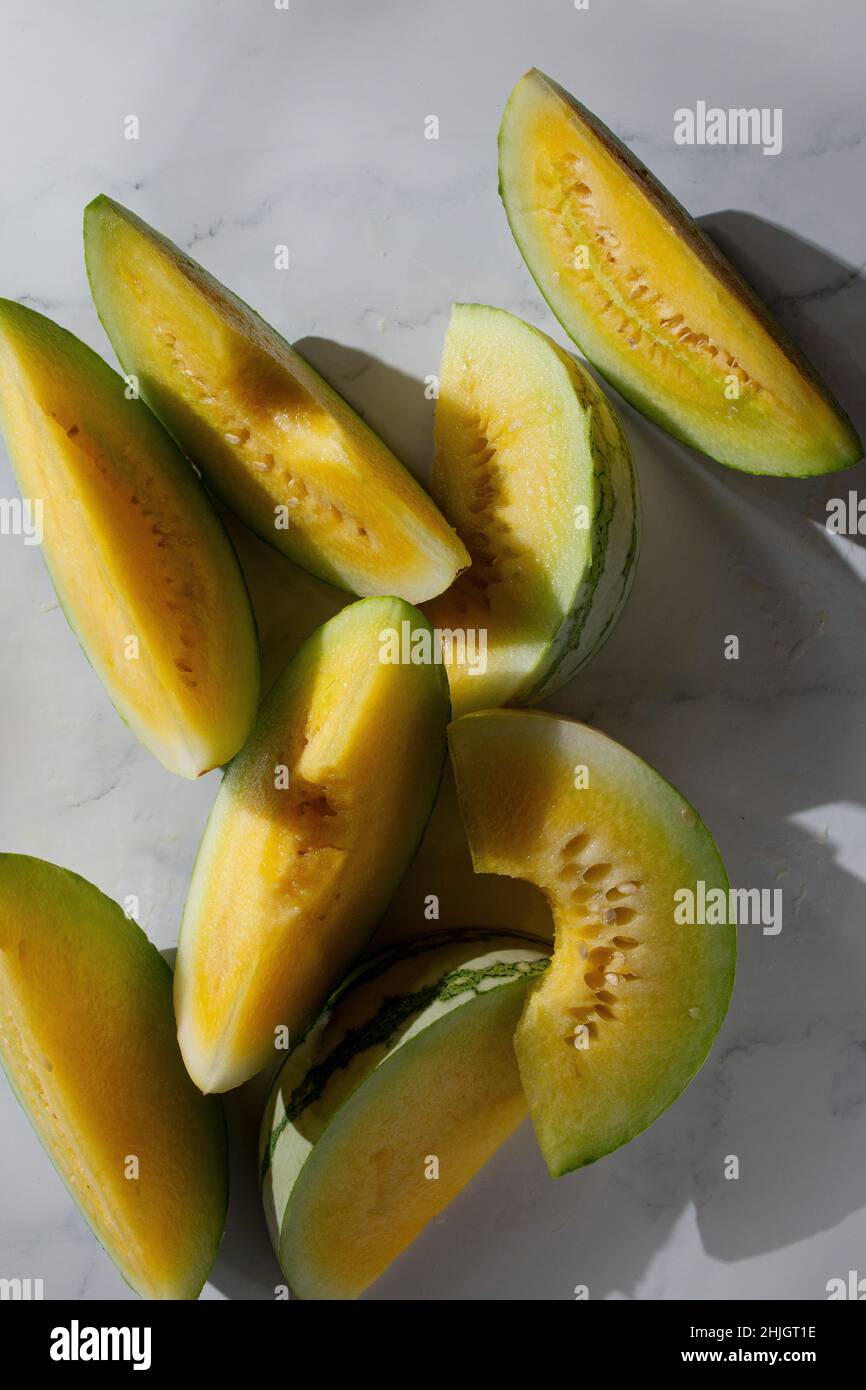 Fette di melone gialle su sfondo marmoreo Foto Stock