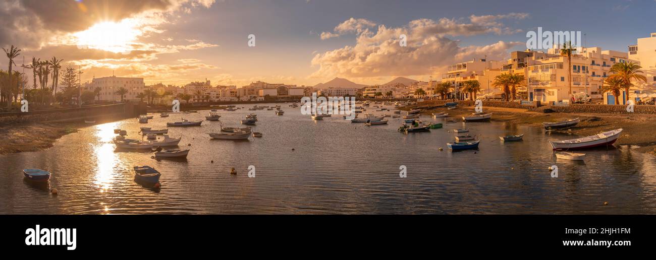 Vista sulla spiaggia di Bahía de Arrecife Marina circondata da negozi, bar e ristoranti al tramonto, Arracife, Lanzarote, Isole Canarie, Spagna, Europa Foto Stock