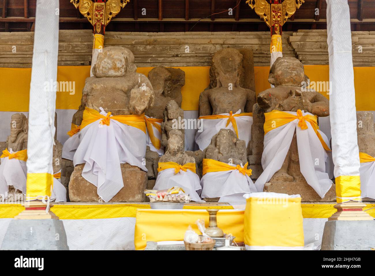 Resti di antiche statue avvolte in tessuto giallo per Mahadeva al tempio indù balinese pura Penataran Sasih, Gianyar, Bali, Indonesia. Foto Stock