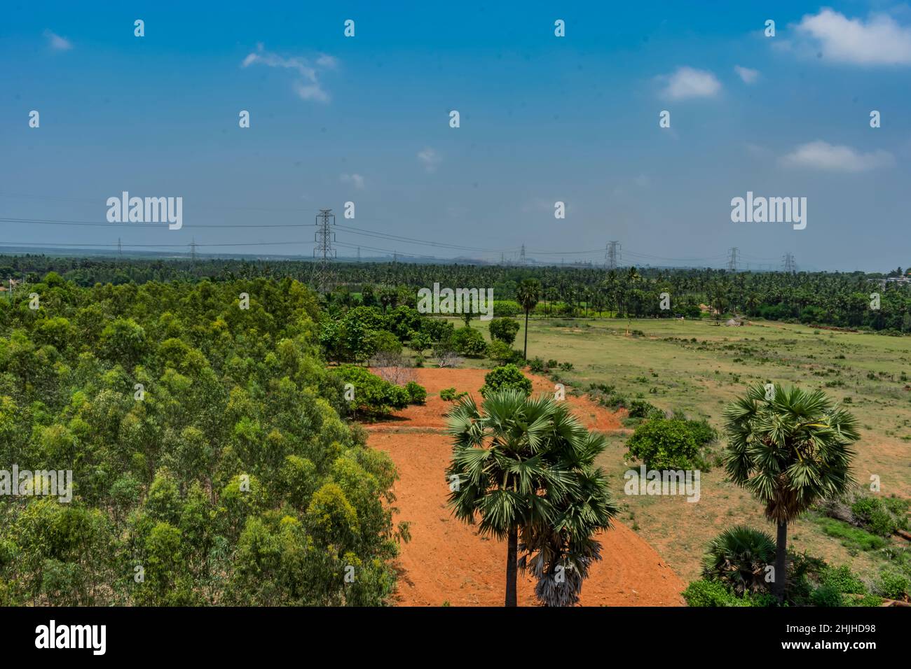 campo verde che guarda impressionante con cielo blu e campo verde vicino a un villaggio rurale Foto Stock