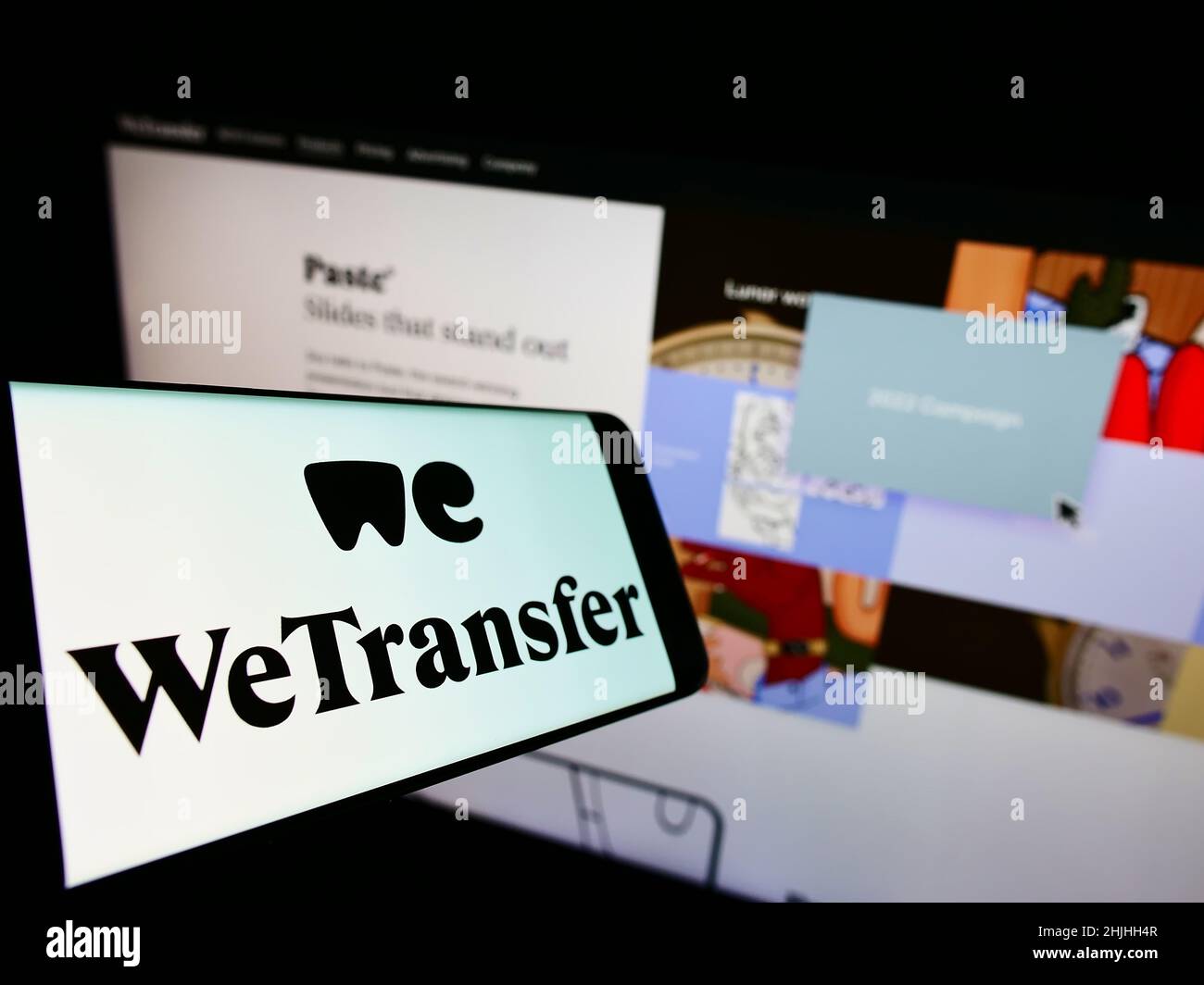 Cellulare con logo della società olandese WeTransfer B.V. di condivisione file sullo schermo di fronte al sito web aziendale. Messa a fuoco al centro-sinistra del display del telefono. Foto Stock