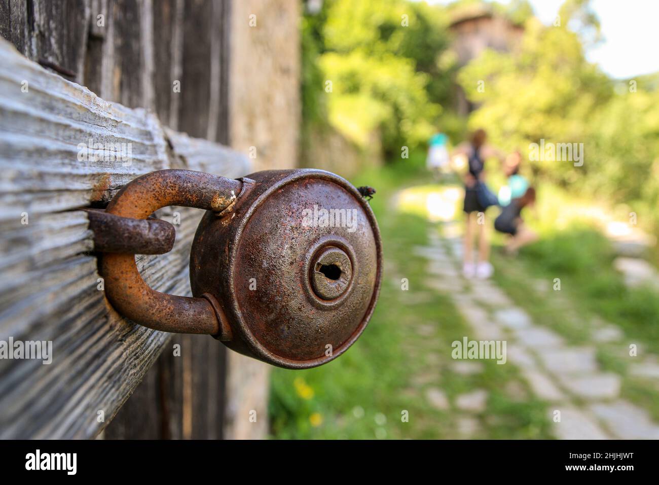 Vecchio fienile arrugginito. Serratura chiusa sulla maniglia metallica di una porta di legno. Chiusura a chiave a porta nel villaggio bulgaro. Foto Stock