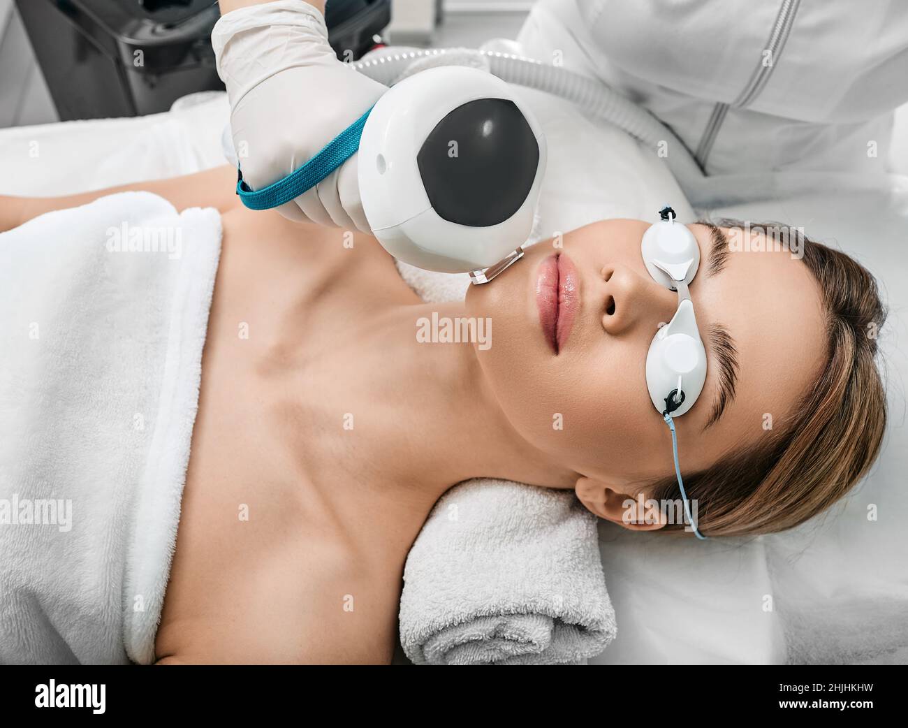 Fotoregiovanimento del volto di una donna utilizzando luce pulsata intensa IPL con un estetista in un salone di cosmetologia per il trattamento della rosacea, rimuovendo macchia marrone Foto Stock