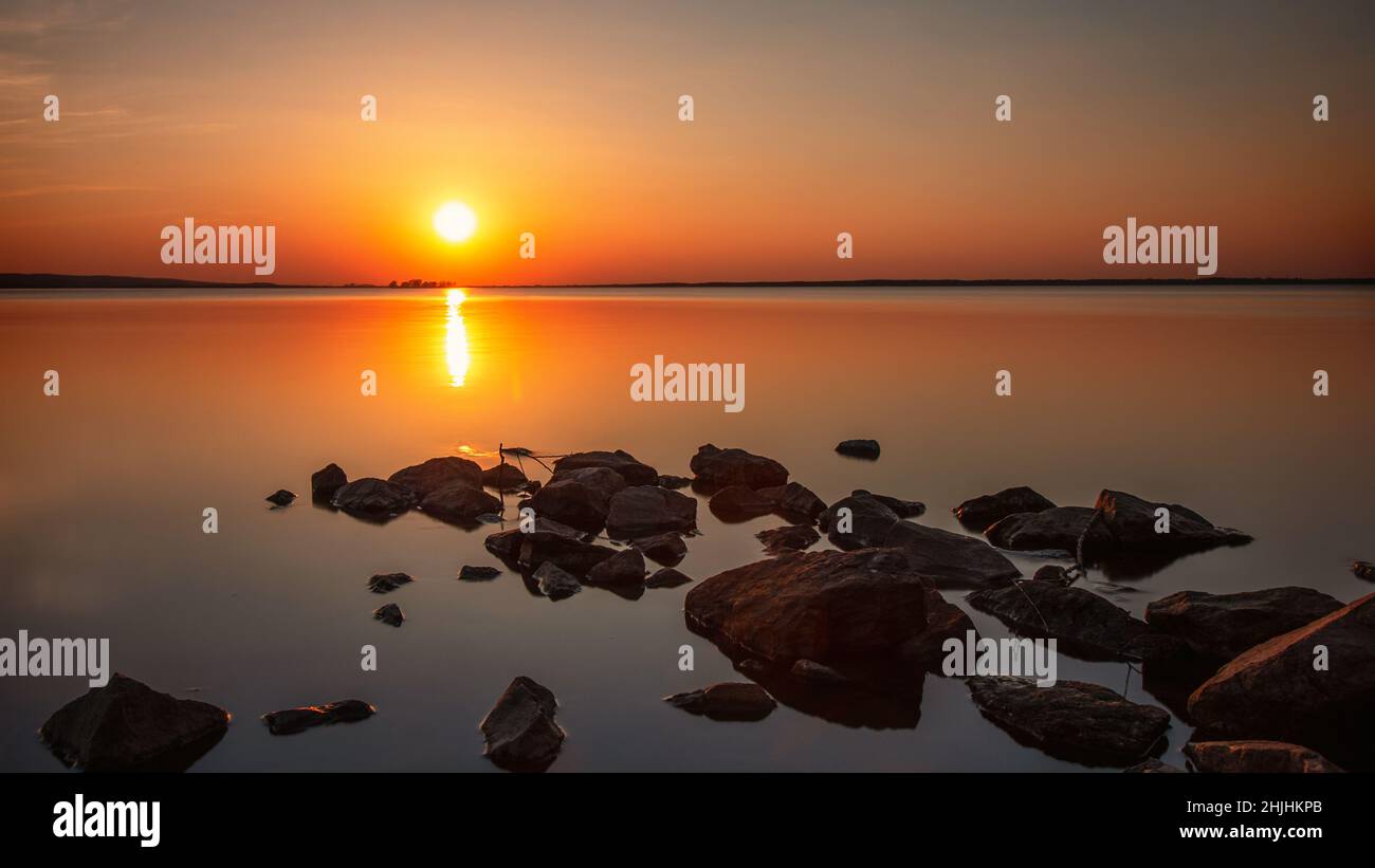 Le pietre conducono nel lago come linee principali. Tramonto al Steinhuder Meer Foto Stock