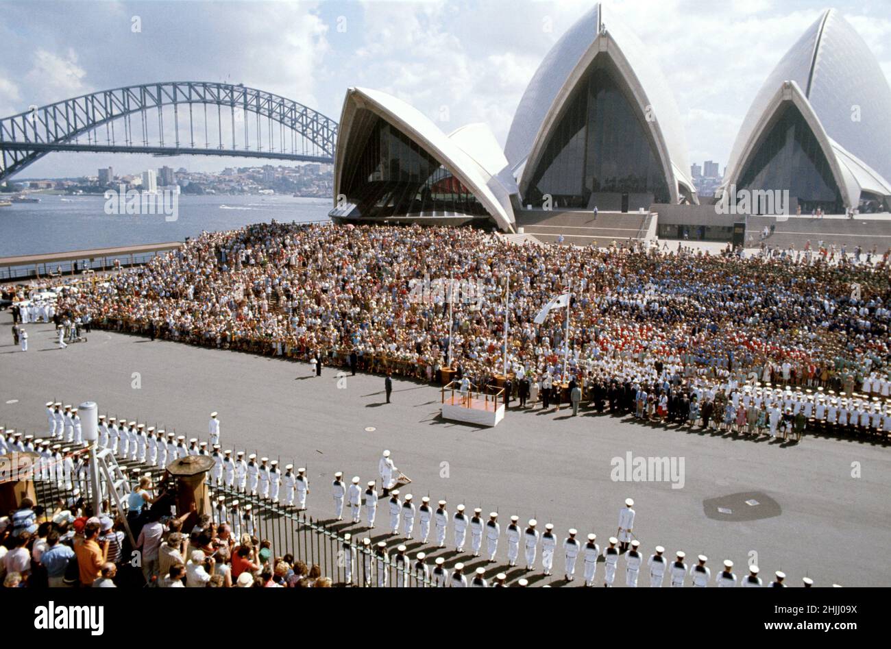 Foto di archivio datata 13/3/1977 della Regina Elisabetta II su un dais fuori dalla Sydney Opera House, E con il Ponte del Porto sullo sfondo, dopo essere sbarcato dal Royal Yacht Britannia ed è stato ricevuto da una guardia navale d'onore da HMAS Nirimba durante il suo tour giubilare d'argento in Australia. Data di emissione: Domenica 30 gennaio 2022. Foto Stock