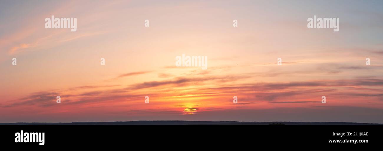 Tramonto in tonalità arancio con nuvole e alberi soffici. Foto Stock
