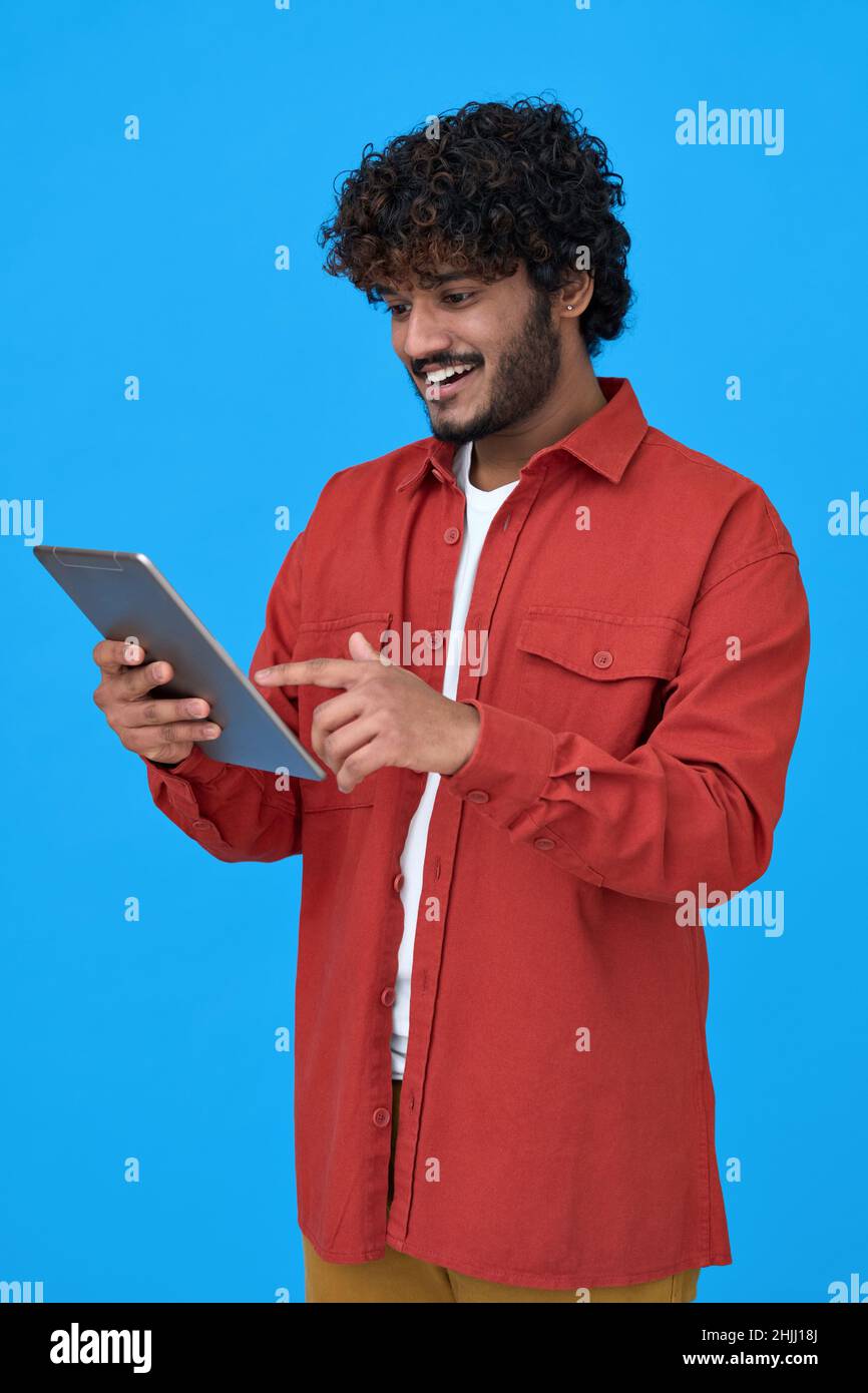 Felice uomo indiano giovane utilizzando tablet digitale isolato su sfondo blu. Foto Stock