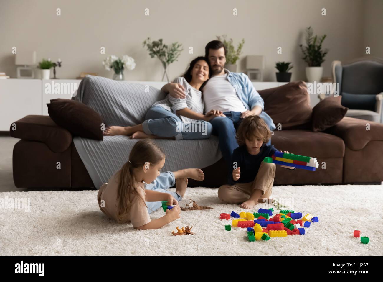 Coppia relax sul divano i loro bambini giocare con mattoni colorati Foto Stock