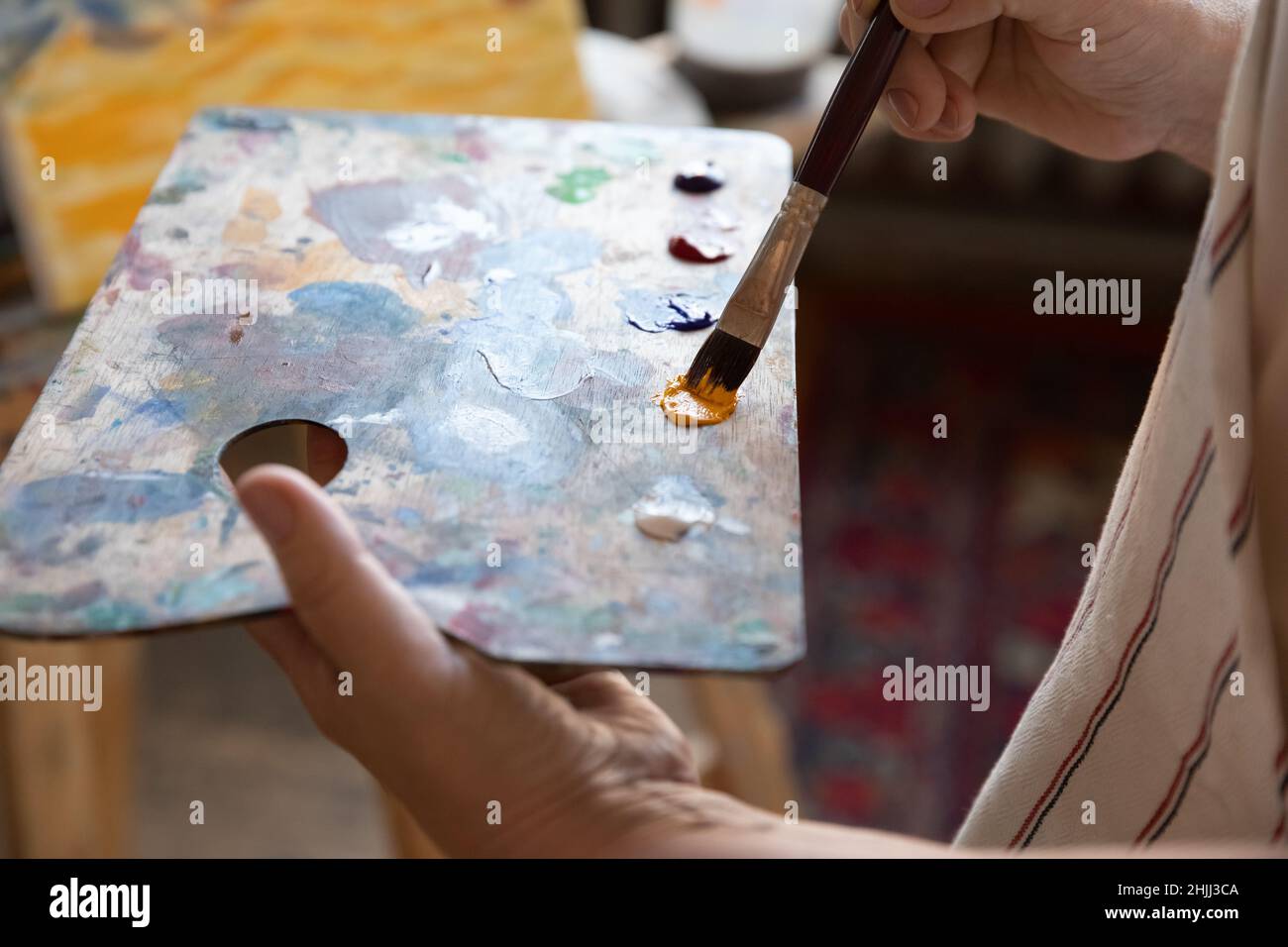 Artista che tiene palette rettangolari, usando il pennello, mescolando le vernici Foto Stock
