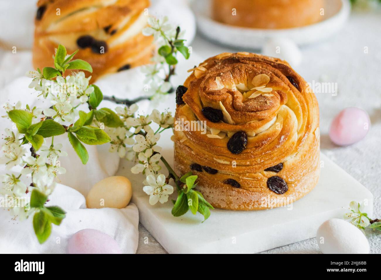 Buona Pasqua. Tradizionale torta di Pasqua , kraffin fatto di casa con uva passa, canditi frutta .fiore di ciliegia su sfondo bianco di legno.fuoco selettivo.Chiudi Foto Stock