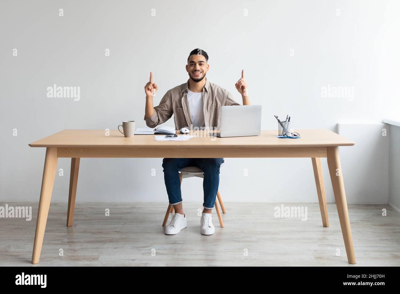 Uomo d'affari felice che punta le dita in su al luogo di lavoro Foto Stock