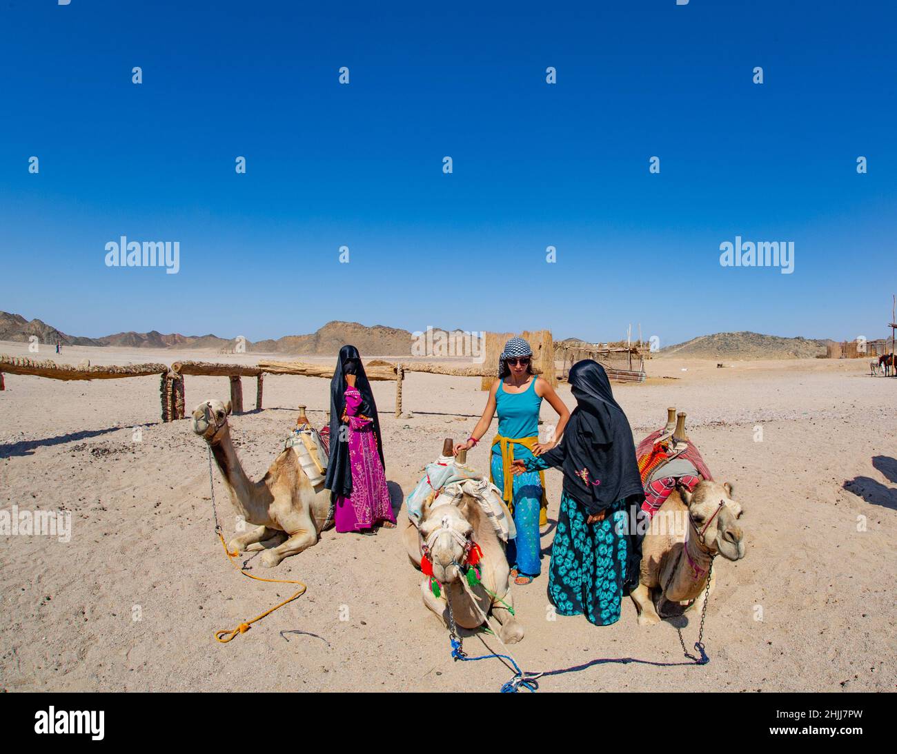 Le donne egiziane in burka aiutando i turisti sui cammelli e poi li cammina intorno Foto Stock