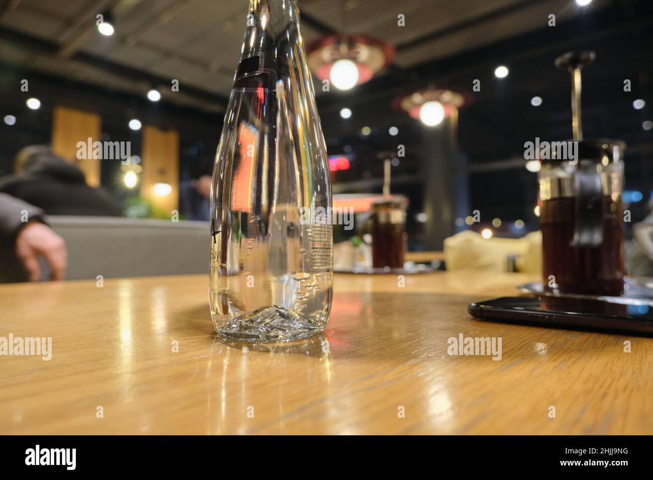 Un bicchiere di bottiglia d'acqua, foto con messa a fuoco selettiva all'interno di un caffè. Foto Stock