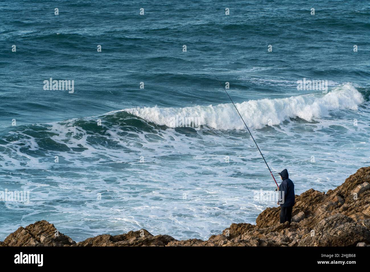 Persona che pesca sulla riva del mare Foto Stock