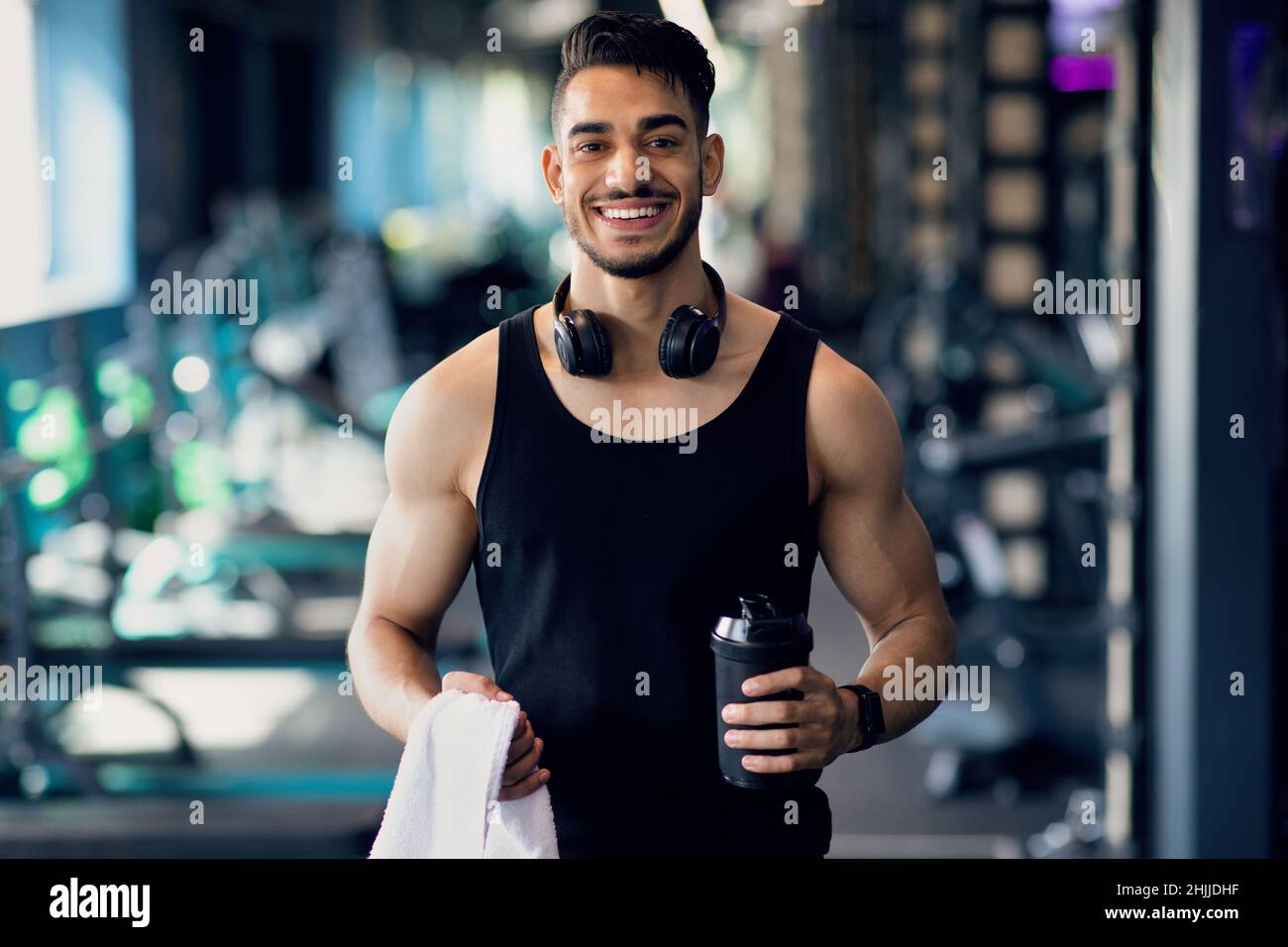 Pronto per la formazione. Felice giovane sportivo arabo Guy in posa presso la palestra interna Foto Stock
