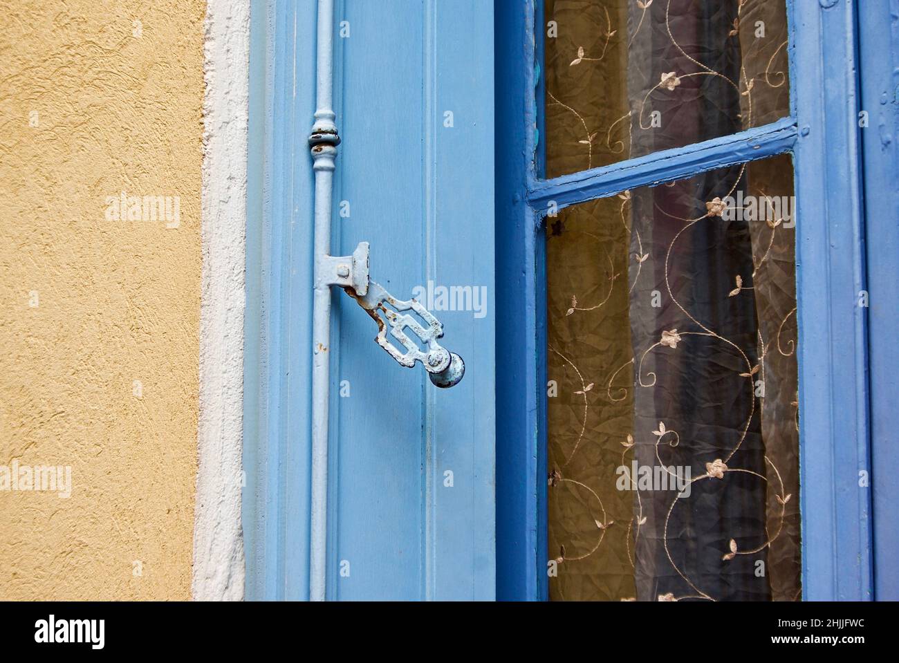 Edificio in pietra gialla con cornice a finestre blu in Provenza in Francia. Foto Stock