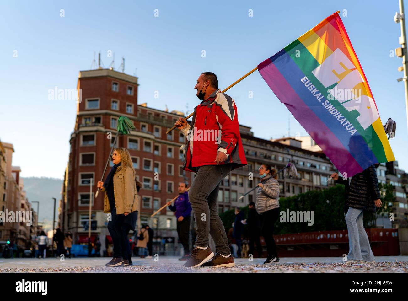 BILBAO, SPAGNA-18 DICEMBRE 2021: Gruppo di addetti alla pulizia protesta per l'aumento del salario. Un uomo che detiene bandiera arcobaleno con parole spagnole sono Unione basca Foto Stock