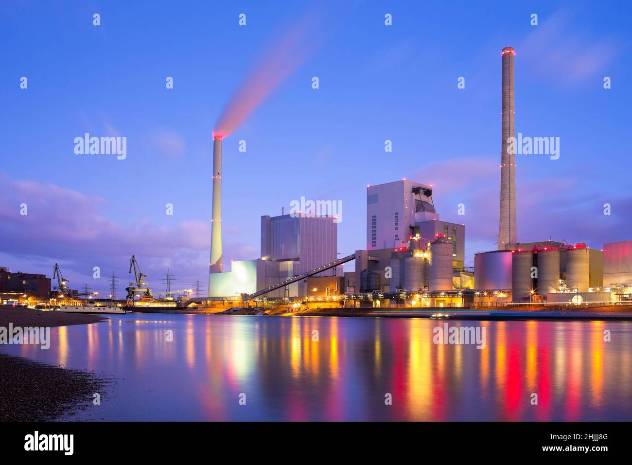 Grande centrale a carbone illuminato con luci riflesse nell'acqua di un fiume Foto Stock